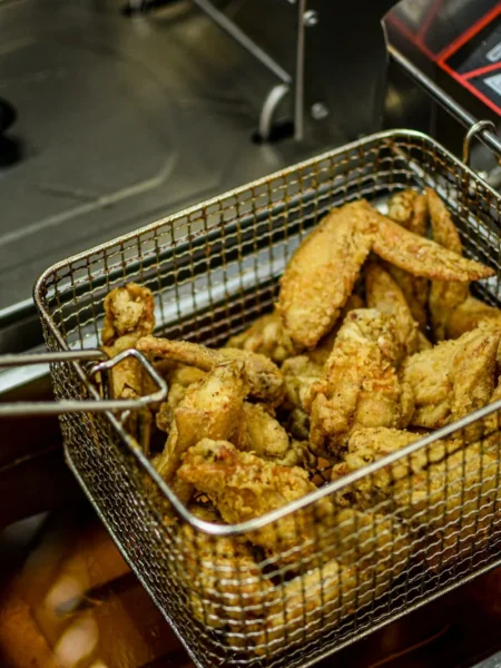 air fryer bbq chicken wings stacked on a tray with glossy brown glaze and crisp golden skin