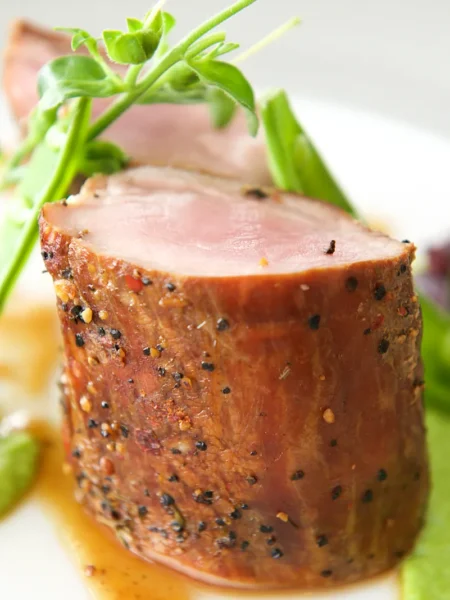 air fryer pork tenderloin sliced into medallions with golden herb crust on a white plate