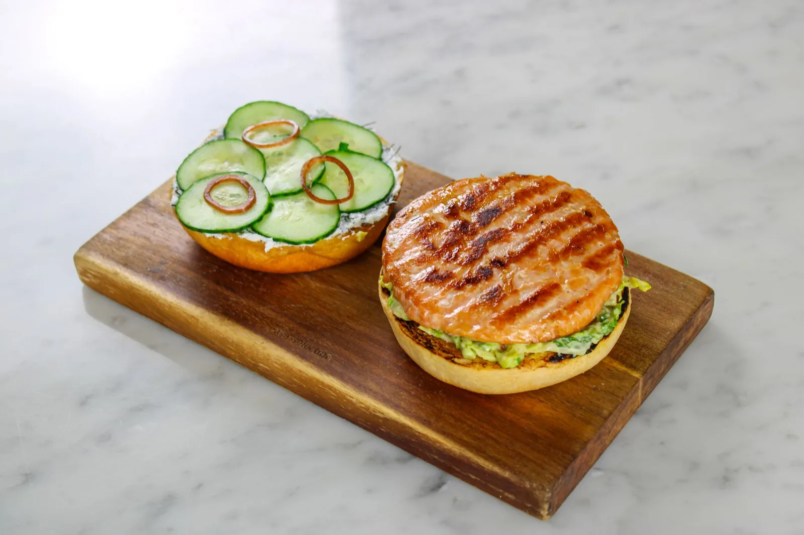 air fryer salmon burgers on a plate with toasted buns and dill sauce