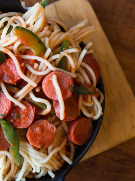 air fryer sausage and peppers with golden pork sausages and red green peppers on a black tray