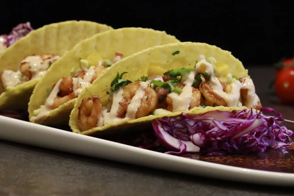 air fryer shrimp tacos with golden shrimp, lime cabbage slaw, and creamy sauce in warm corn tortillas