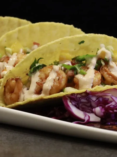 air fryer shrimp tacos with golden shrimp, lime cabbage slaw, and creamy sauce in warm corn tortillas