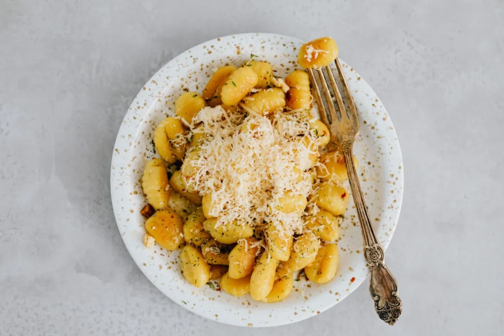 air fryer smashed potatoes with golden crispy edges, melted parmesan, and chopped chives on a white plate