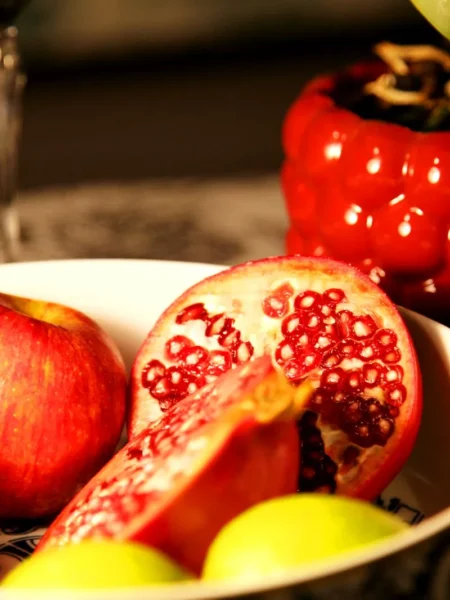 apples with hot honey and pomegranate seeds showing sliced honeycrisp apples drizzled with chili honey and red arils on a white plate
