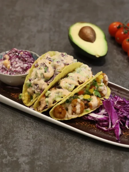 baja shrimp tacos recipe with golden fried shrimp, creamy cabbage slaw, and warm corn tortillas on a plate