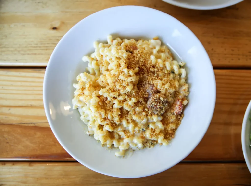 baked mac and cheese recipe with breadcrumbs showing golden crispy topping and creamy cheddar pasta in a glass dish