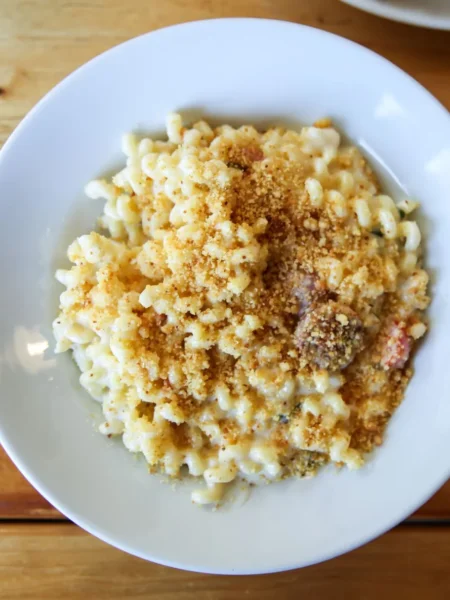 baked mac and cheese recipe with breadcrumbs showing golden crispy topping and creamy cheddar pasta in a glass dish