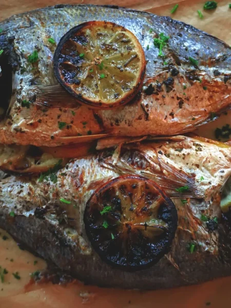 baked tilapia recipe for weeknight dinner with lemon slices and parsley on a sheet pan, golden flaky fillets