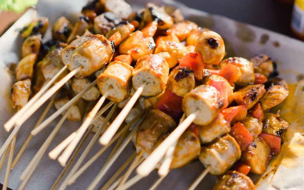 bang bang chicken skewers grilled with red pepper on sticks with creamy spicy sauce drizzle