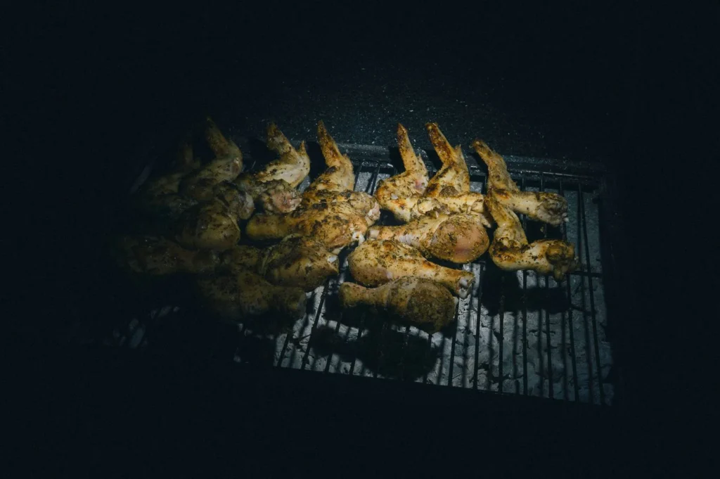 bbq chicken leg quarters with golden crispy skin brushed in tomato bbq sauce on a grill tray