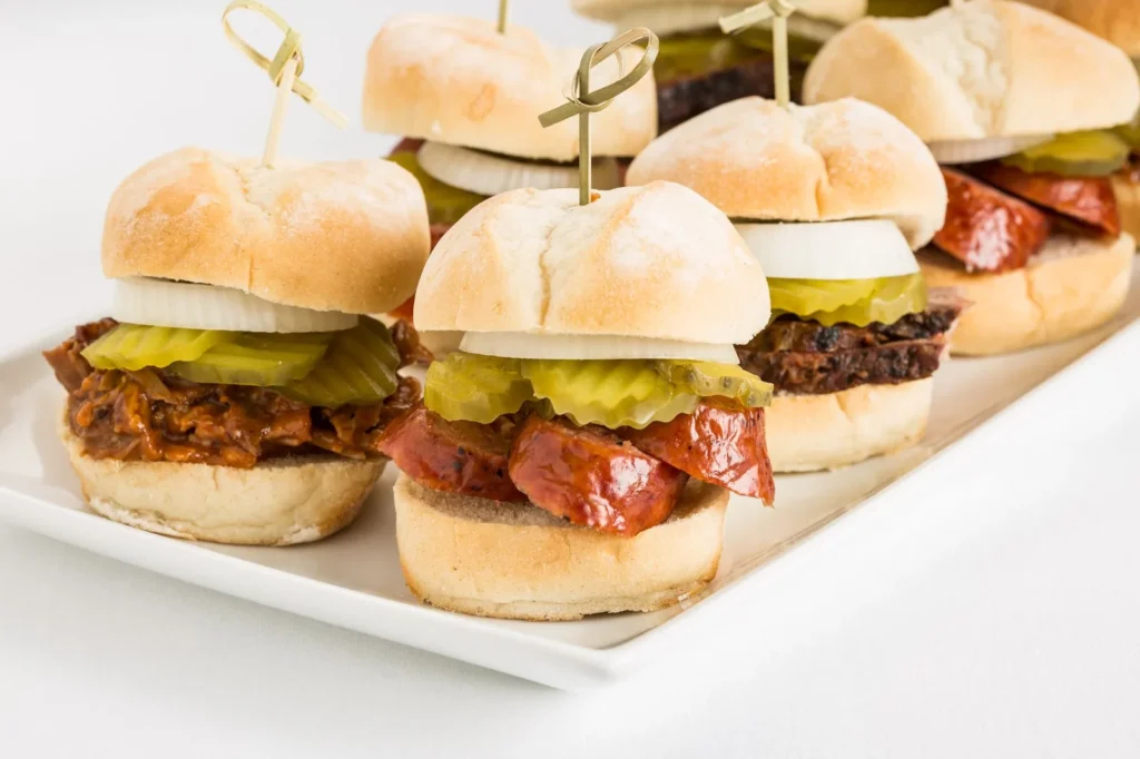 bbq chicken sliders recipe with shredded barbecue chicken, melted cheddar, and red onion on soft golden potato buns