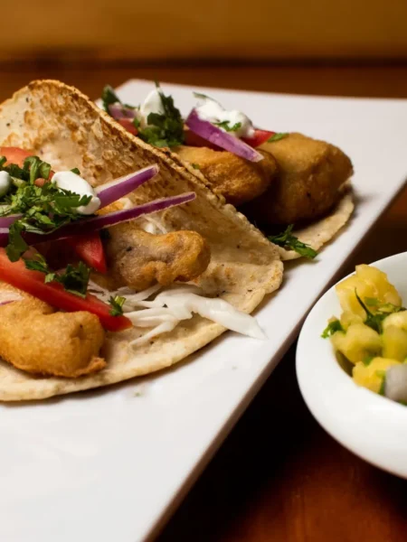 bbq chicken tacos with pineapple salsa on warm corn tortillas topped with diced pineapple, red onion, and cilantro