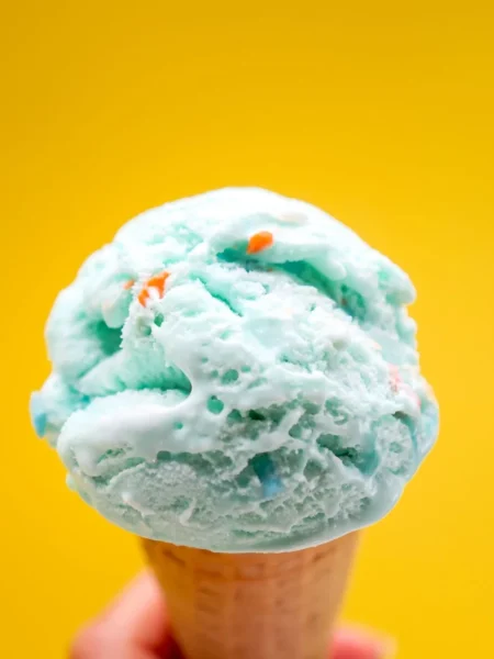blue moon ice cream scoop with bright blue custard texture in a sugar cone on a white plate