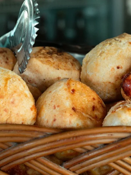 brazilian cheese bread recipe showing golden pão de queijo rolls with cracked crisp tops and cheesy pull-apart centers on a tray