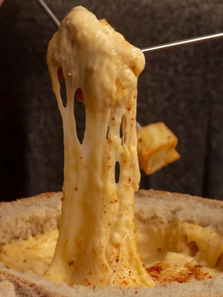 buffalo chicken dip recipe for game day in a baking dish with melted cheddar, blue cheese, and shredded chicken topped with green onion