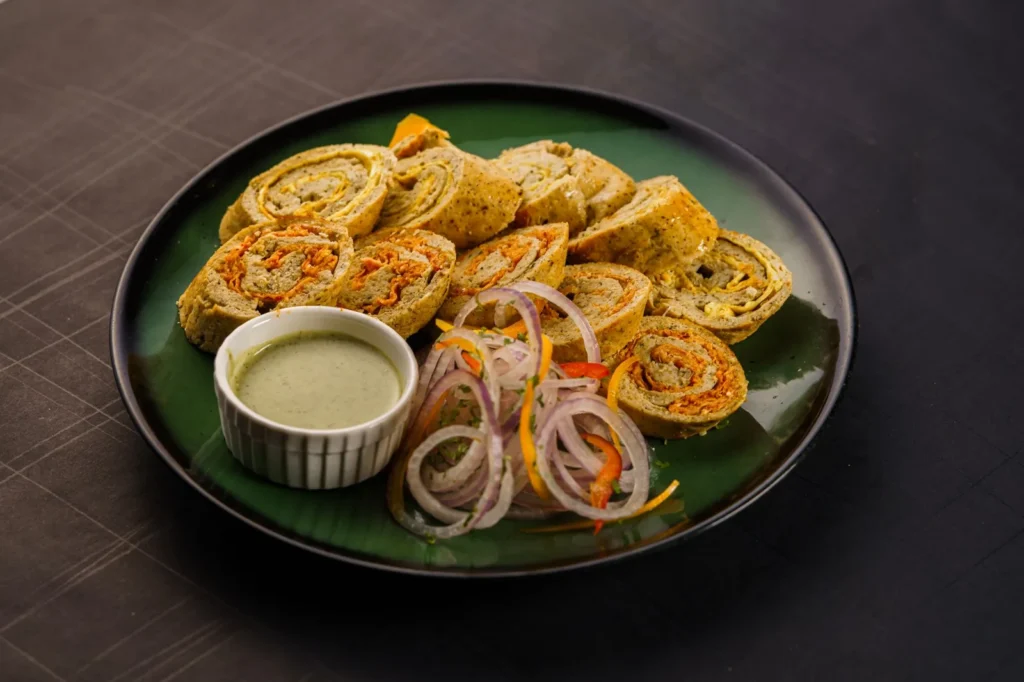 buffalo chickpea pinwheels sliced into spiral tortilla rolls with orange buffalo chickpea filling and celery bits