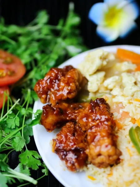 buttermilk mango cilantro chicken with coconut rice served in a bowl with golden seared chicken pieces over white coconut rice and fresh cilantro