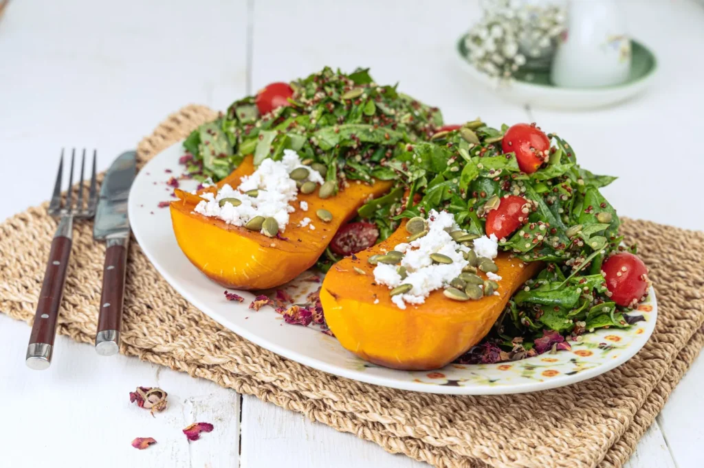 butternut squash and cranberry quinoa salad recipe with roasted golden squash cubes, red cranberries, and toasted pumpkin seeds in a white bowl