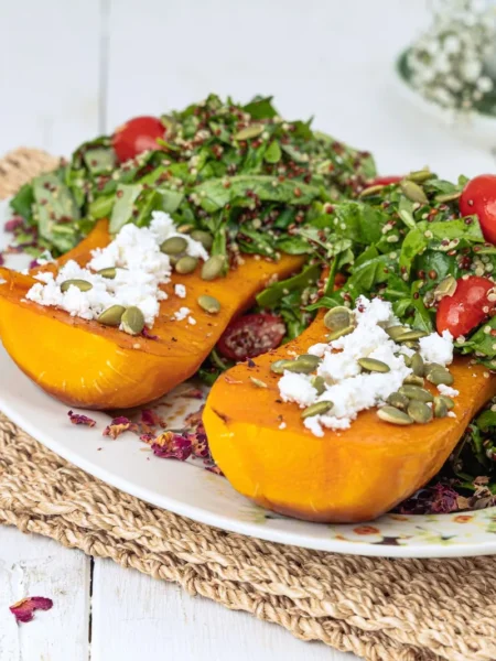 butternut squash and cranberry quinoa salad recipe with roasted golden squash cubes, red cranberries, and toasted pumpkin seeds in a white bowl