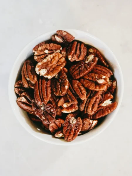 buttery brown sugar pecan acorn squash roasted with caramel glaze and toasted pecans on a sheet pan