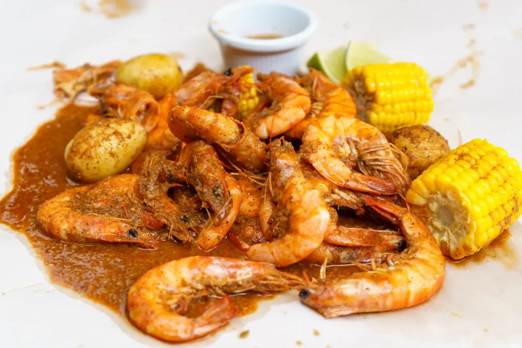 cajun butter sauce for seafood poured over peeled shrimp in a skillet with garlic and parsley