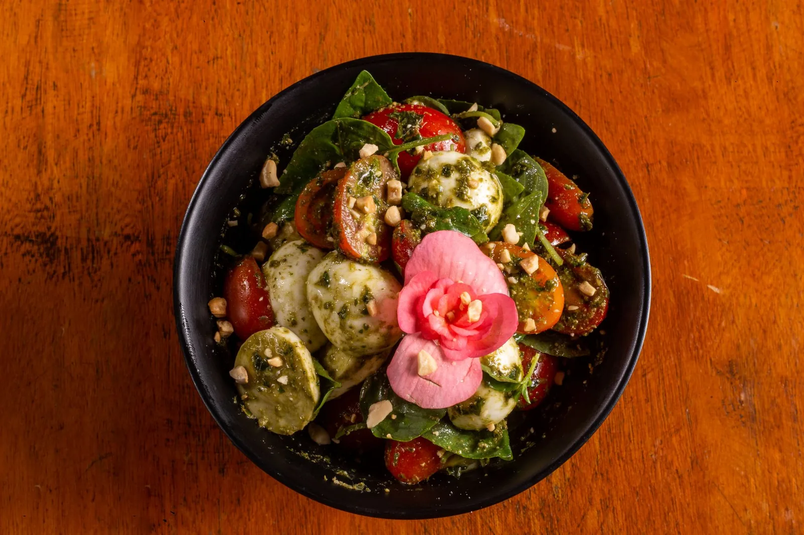 caprese pasta salad with pesto in white bowl with tomatoes and mozzarella