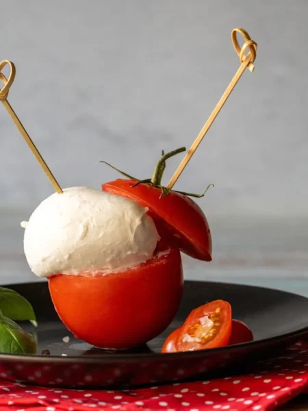 caprese skewers recipe for appetizers with cherry tomato halves, fresh mozzarella balls, and basil on wooden sticks