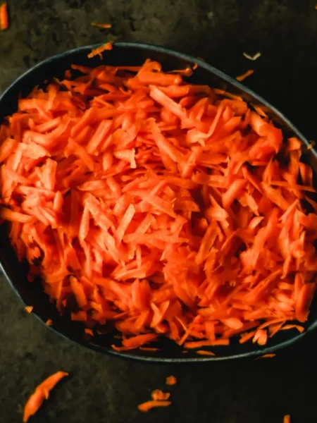 carrot pancakes recipe with finely grated carrot flecks, golden edges, and a maple syrup drizzle on a white plate