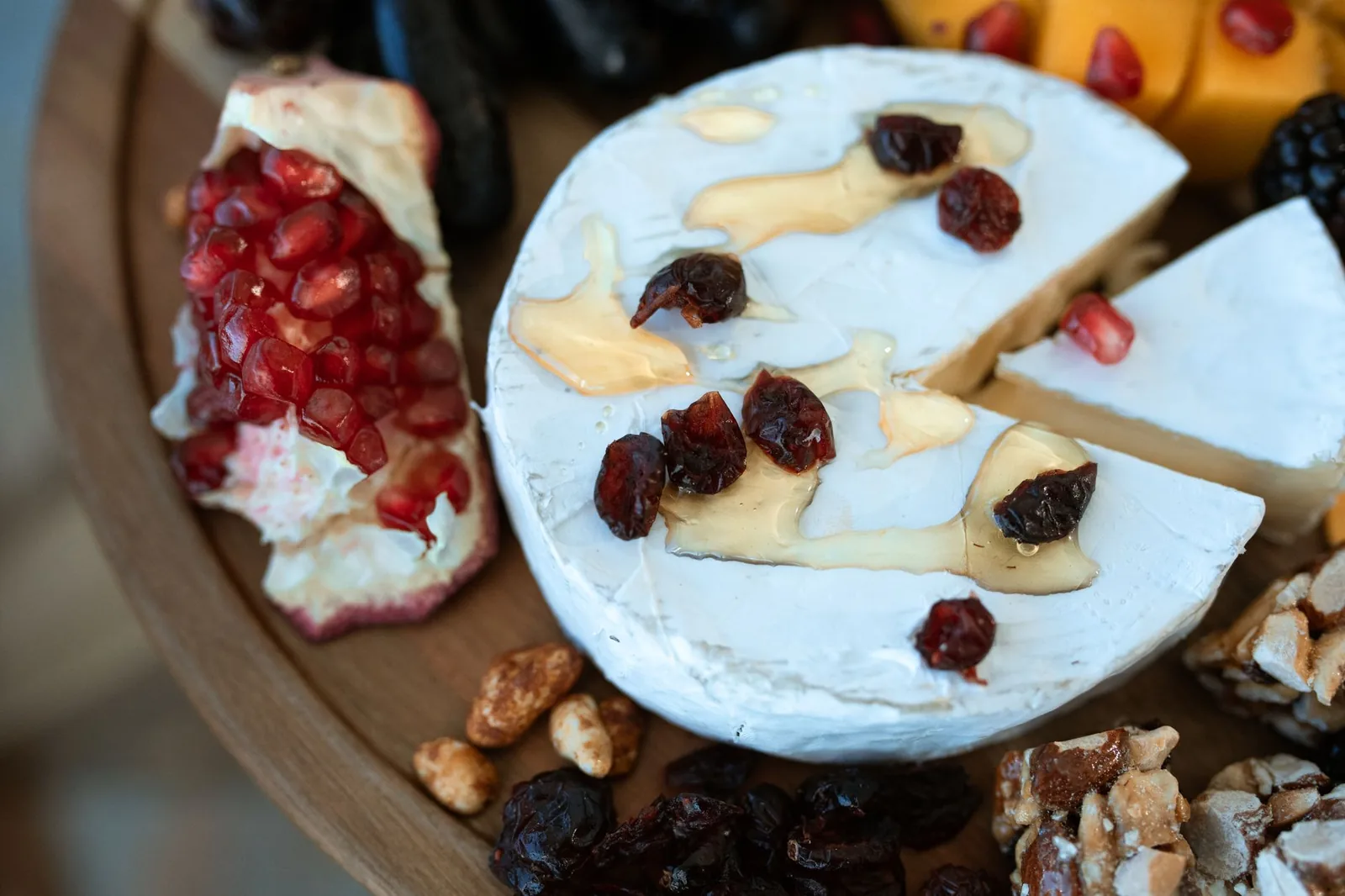 cheese ball recipe for parties showing a round cream cheese ball coated in toasted pecans and dried cranberries on a white platter