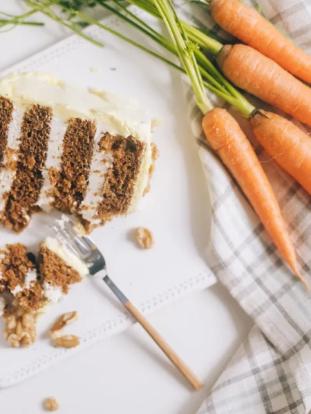 cheesecake factory carrot cake with three spiced layers, toasted walnuts, and thick cream cheese frosting on a white plate