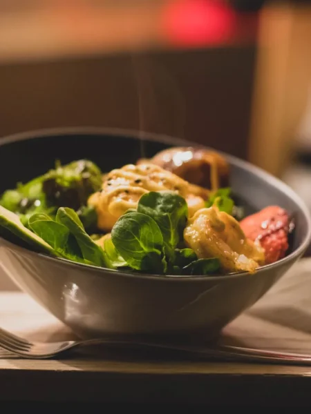 chicken and mango salad in a white bowl with diced mango, golden chicken strips, red pepper, and cilantro