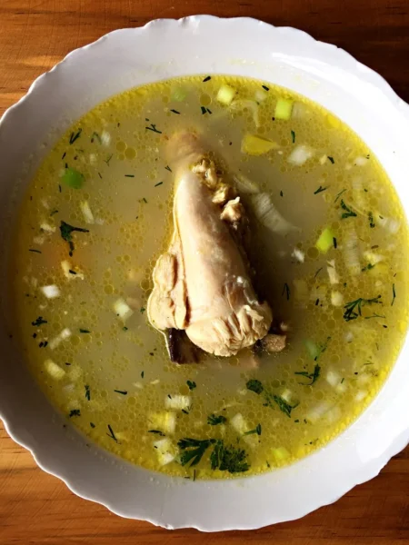 chicken and rice soup in a white bowl with tender chicken, soft white rice, and carrot slices in clear broth