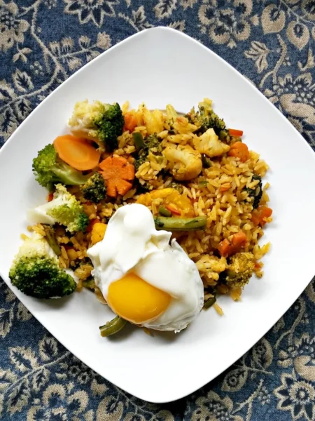 chicken fried rice recipe with diced chicken, green peas, carrots, and scrambled egg on a white plate