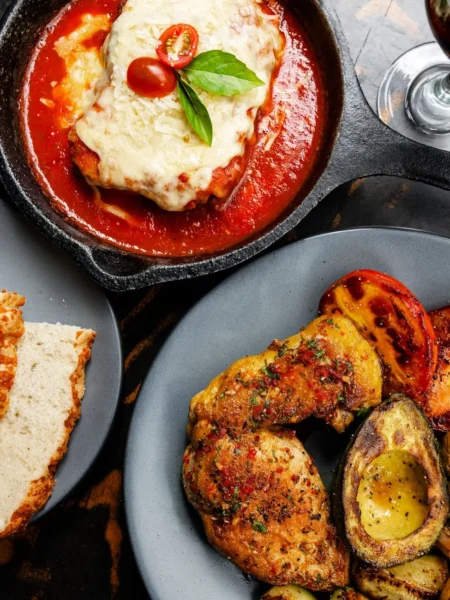 chicken parmesan meatballs baked with marinara sauce and melted mozzarella and parmesan on top in a ceramic dish