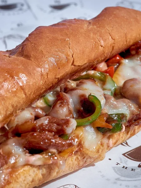 chicken philly cheesesteak with thin chicken strips, sauteed peppers and onions, and melted provolone in a toasted hoagie roll