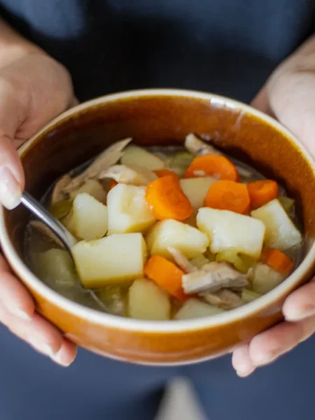 chicken potato soup recipe in a white bowl with tender chicken pieces, diced yukon gold potatoes, and chopped parsley on top