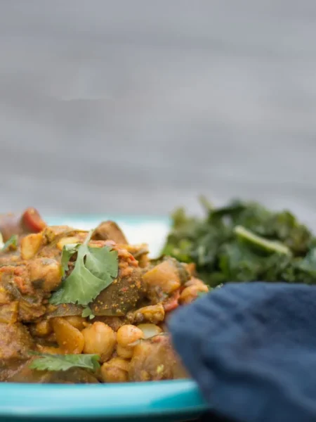 chickpea and spinach curry in a skillet with soft chickpeas, wilted green spinach, and red tomato gravy topped with lemon