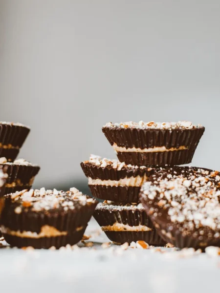 chocolate peanut butter mini cheesecakes with oreo crust, peanut filling, and glossy chocolate top in paper liners