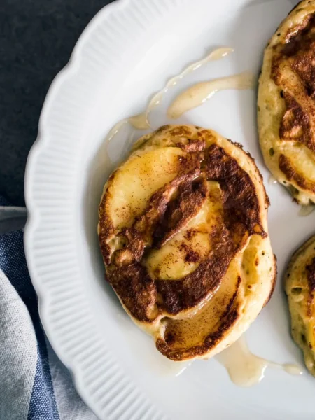 cinnamon french toast roll ups with golden crispy bread coils dusted in cinnamon sugar on a white plate