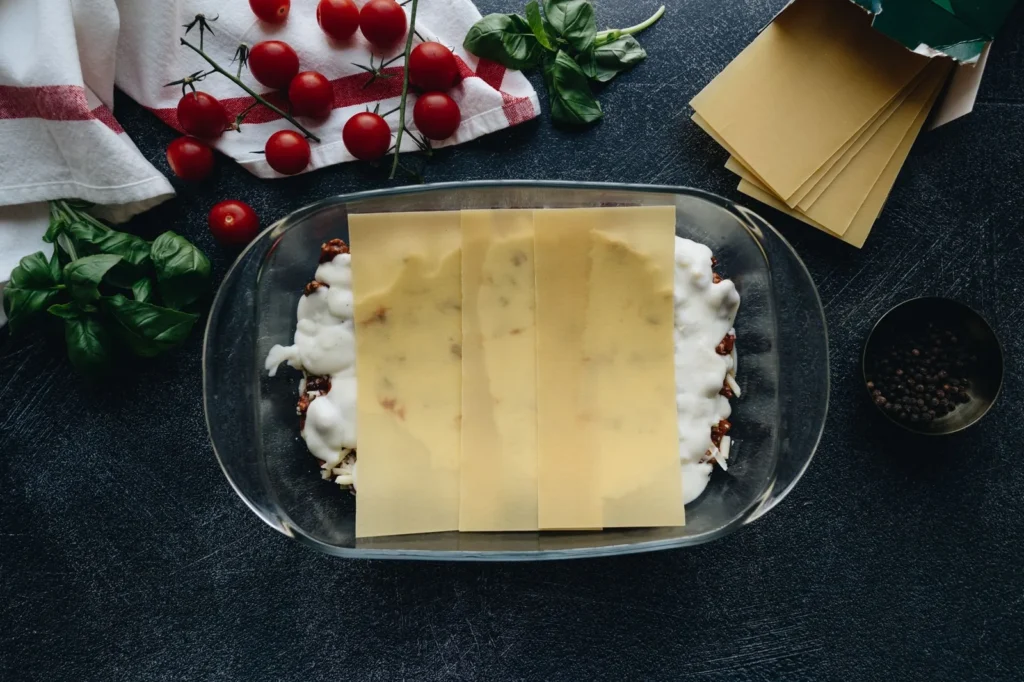 classic lasagna with bechamel showing pasta layers, meat ragù, and golden bechamel crust in a baking dish