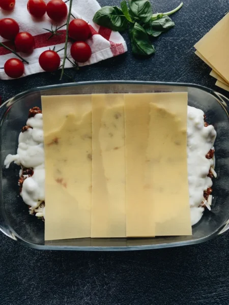 classic lasagna with bechamel showing pasta layers, meat ragù, and golden bechamel crust in a baking dish