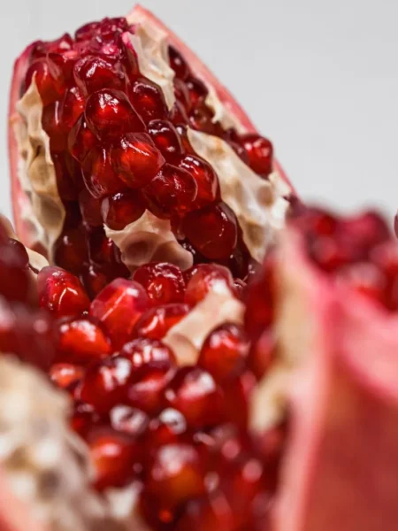 cranberry pomegranate mimosas recipe in clear flutes with ruby juice, prosecco foam, and floating pomegranate arils
