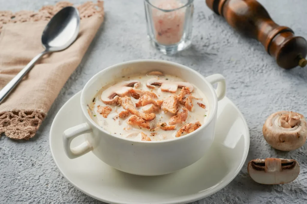creamy chicken and rice soup in a white bowl with tender chicken pieces, soft rice, and carrot slices in a silky broth