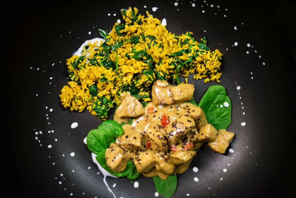 creamy chicken orzo with spinach and lemon in a skillet with wilted greens and lemon slices