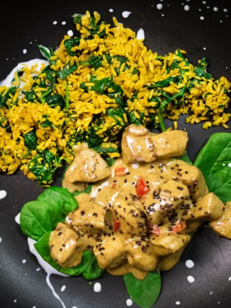 creamy chicken orzo with spinach and lemon in a skillet with wilted greens and lemon slices