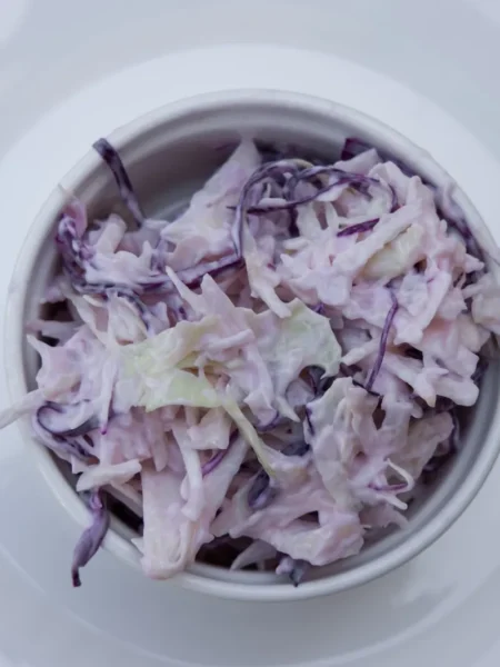 creamy coleslaw 2 with green and red cabbage ribbons, grated carrot, and a thick mayonnaise dressing in a white bowl