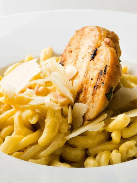creamy lemon chicken pasta with seared chicken strips, penne in a glossy parmesan lemon sauce, and parsley on a white plate