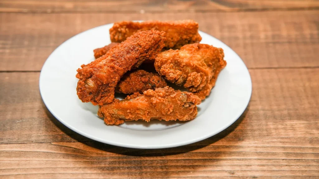 crispy baked chicken wings with golden paprika skin and buffalo butter glaze on a wire rack tray