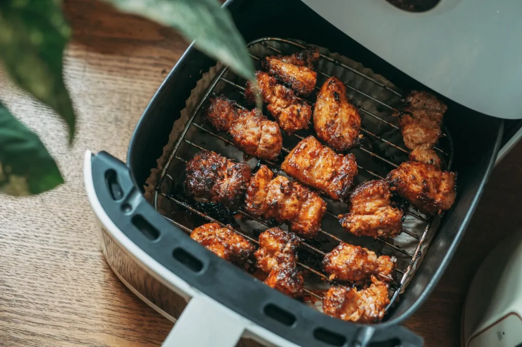 dry rub air fryer chicken thighs with golden crispy skin and charred spice crust on a black tray