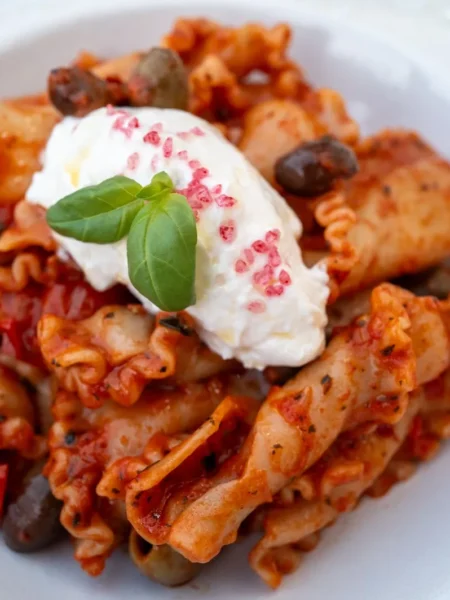 easy lemon ricotta pasta in a white bowl with rigatoni coated in creamy ricotta lemon sauce and basil